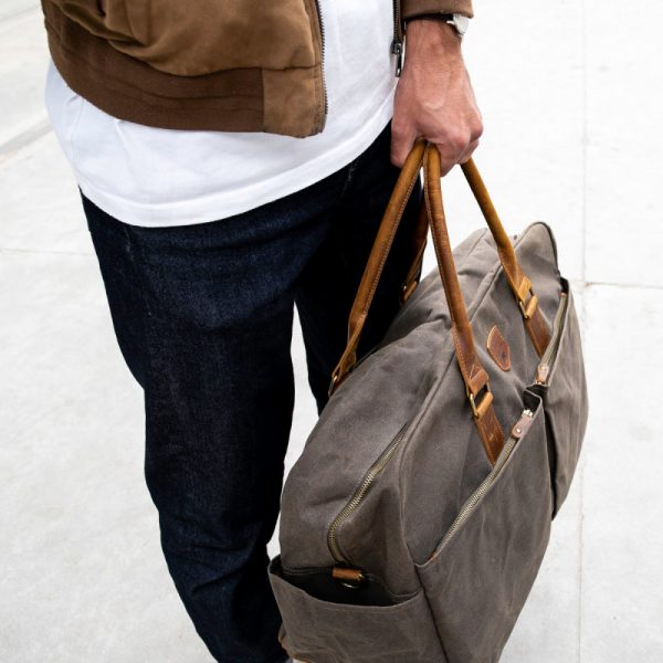 Weekender Reisetasche Alaskan Maker Khaki mit hellem Leder, vom Mann am Griff getragen