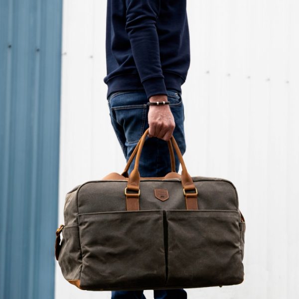 Weekender Reisetasche Alaskan Maker Khaki mit hellem Leder, von Mann am Griff getragen